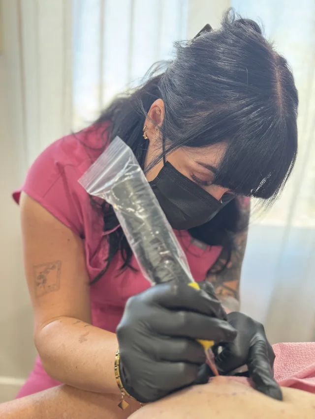 Areola studio demonstration: a masked practitioner works with a tattoo machine